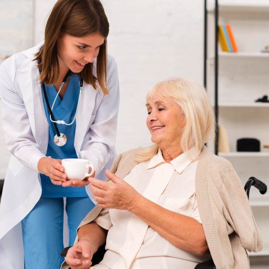carer giving elderly lady cup of tea